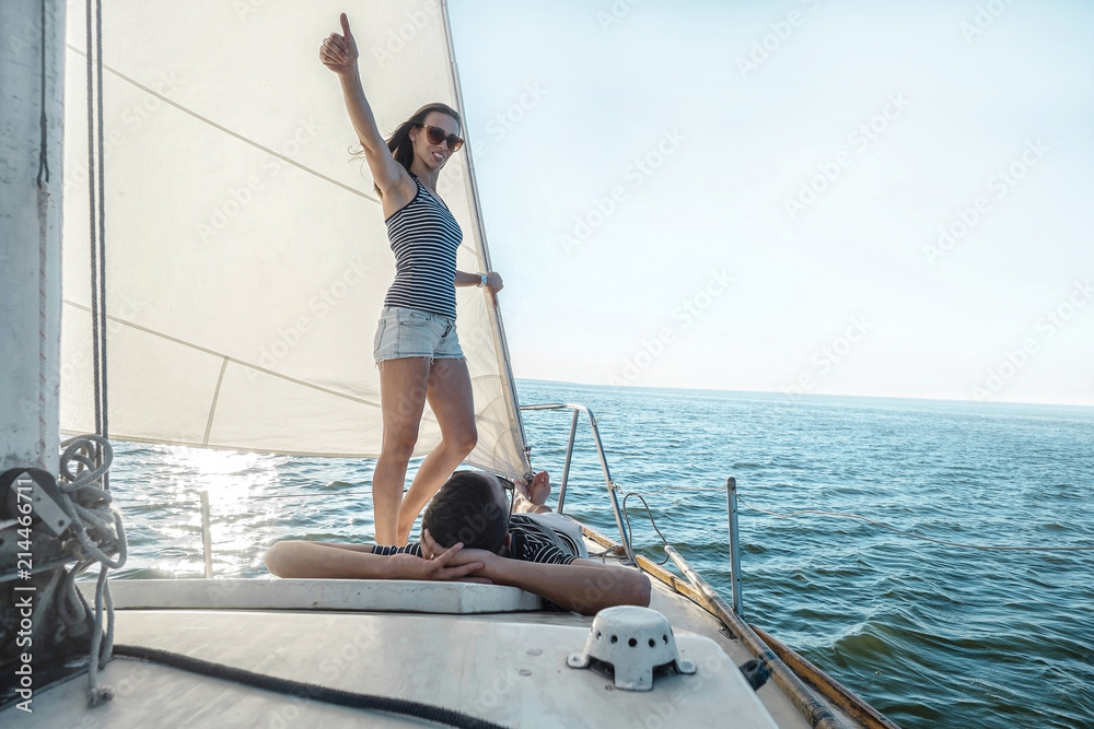 Romantic couple in love on sail boat at sunset under sunlight