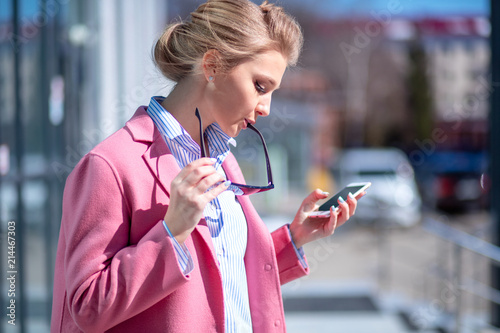 young awesome woman dialing the number. order sushy by phone. girl with glasses on her lips looking at the screen of the cell phone photo