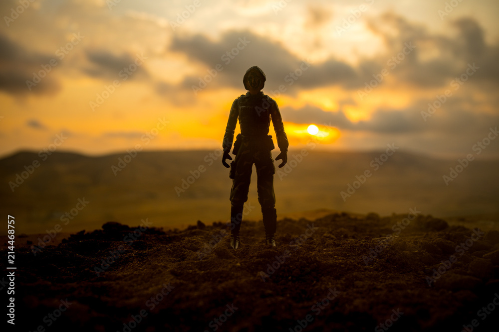 Silhouette of military soldier or officer with weapons at sunset. shot, holding gun, colorful sky, mountain, background. Decoration with toy soldier
