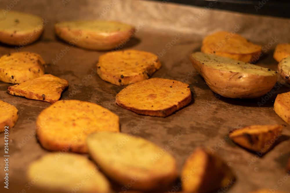 Scheiben von Kartoffeln und Süßkartoffeln auf Backblech im Ofen Scheiben von Kartoffeln und Süßkartoffeln auf Backblech im Ofen