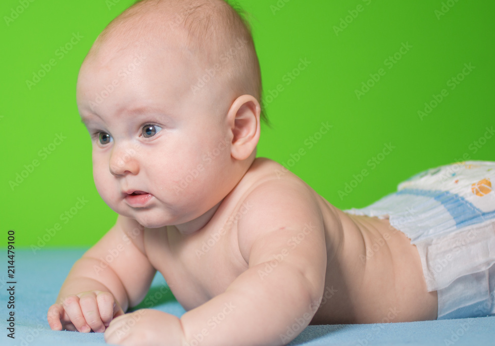 portrait of a beautiful newborn baby who smiles on a blue sheet in diapers portrait of a beautiful newborn baby who smiles on a blue sheet in diapers