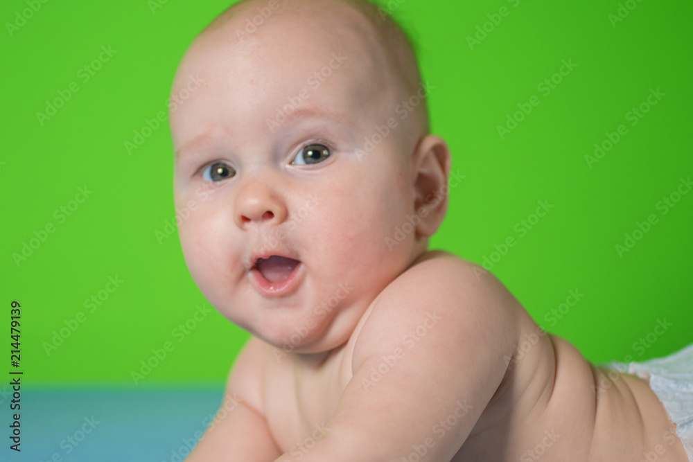 portrait of a beautiful newborn baby who smiles on a blue sheet in diapers portrait of a beautiful newborn baby who smiles on a blue sheet in diapers