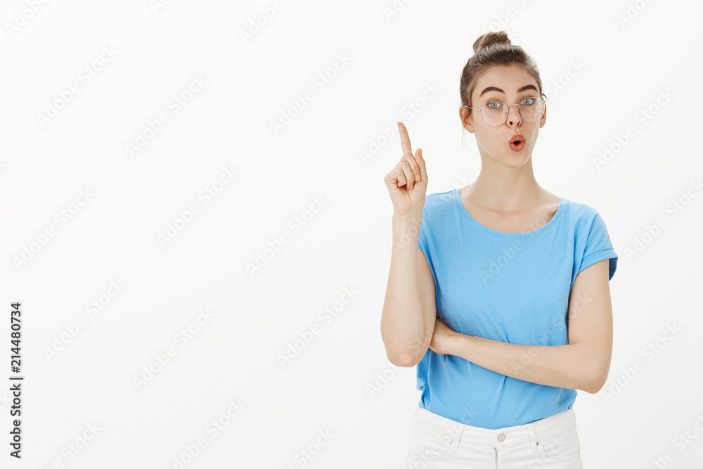 I have fantastic idea. Portrait of positive friendly european female in glasses, folding lips and raising index finger in eureka gesture, suggesting great solution or plan, sharing thoughts with team I have fantastic idea. Portrait of positive friendly european female in glasses, folding lips and raising index finger in eureka gesture, suggesting great solution or plan, sharing thoughts with team