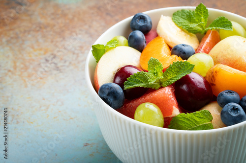 Bowl of healthy fresh fruit salad on a blue rusty background. with copy space
