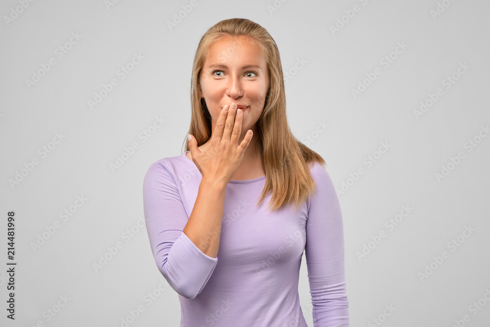 The emotional girl heard a funny joke. Studio portrait of joyful charming European woman with blonde hair, covering her mouth with palm and laughing loudly, hearing funny joke or watching Comedy show The emotional girl heard a funny joke. Studio portrait of joyful charming European woman with blonde hair, covering her mouth with palm and laughing loudly, hearing funny joke or watching Comedy show