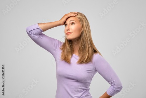 Regrets wrongdoing. Closeup portrait of confused young woman, slapping hand on head, having duh moment, gray studio background