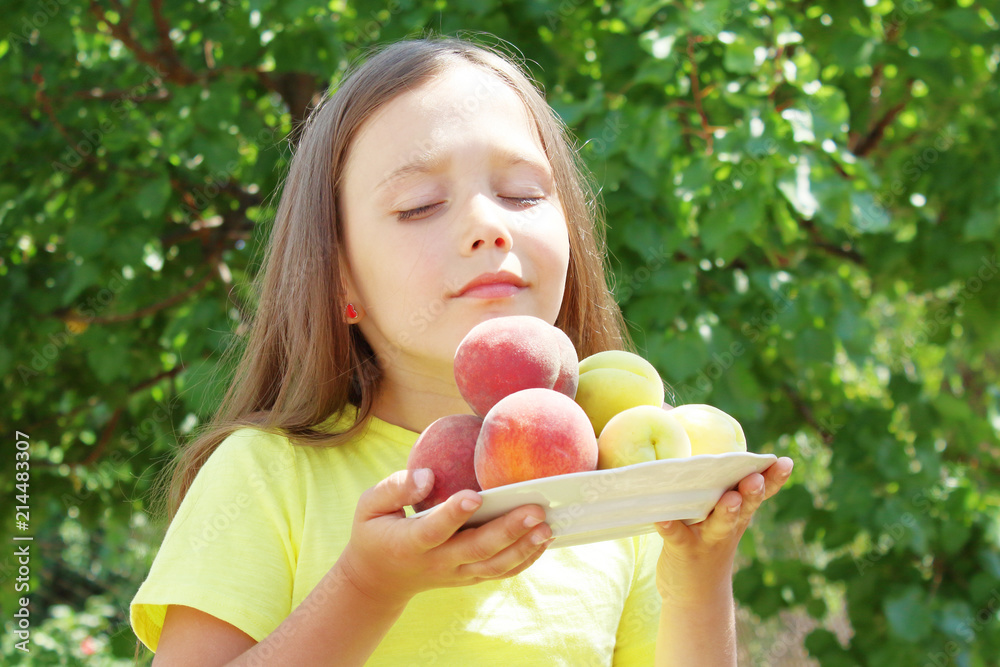 little brunette girl holding peaches and apricots in her hands, sniffing fruit little brunette girl holding peaches and apricots in her hands, sniffing fruit