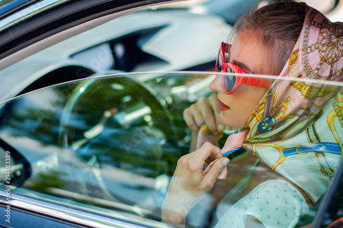 Beautiful fashion woman with red lips and sunglasses in the car.