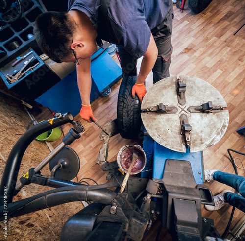 Professional car mechanic replace tire on wheel.