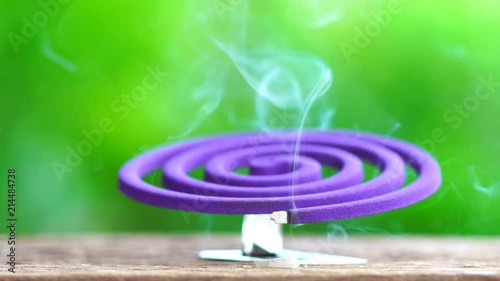 4K resolution : Violet mosquito repellent and white smoke on wooden table with green blur light space background