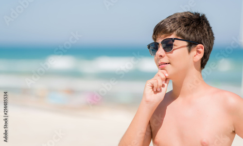 Young child on holidays by the beach serious face thinking about question, very confused idea