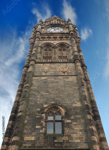 the tall clock tower of historic rochdale town hall in lancashire with blue summer sky and white clouds