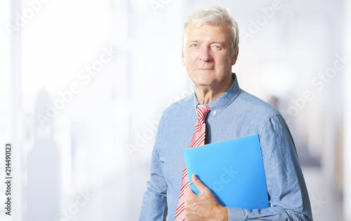 Executive senior manager portrait. A senior businessman standing at the office while looking at camera and smiling. 