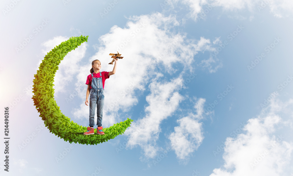 Concept of careless happy childhood with girl on green moon Concept of careless happy childhood with girl on green moon