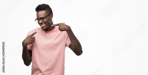 Young african american man wearing pink t-shirt smiling confident showing and pointing with fingers teeth and mouth. Health concept.