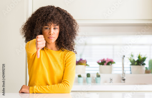 African american woman wearing yellow sweater at kitchen looking unhappy and angry showing rejection and negative with thumbs down gesture. Bad expression.