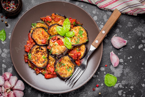 Fried eggplant slices with tomatoes, herbs and garlic, tasty vegetarian summer lunch. Grilled aubergine