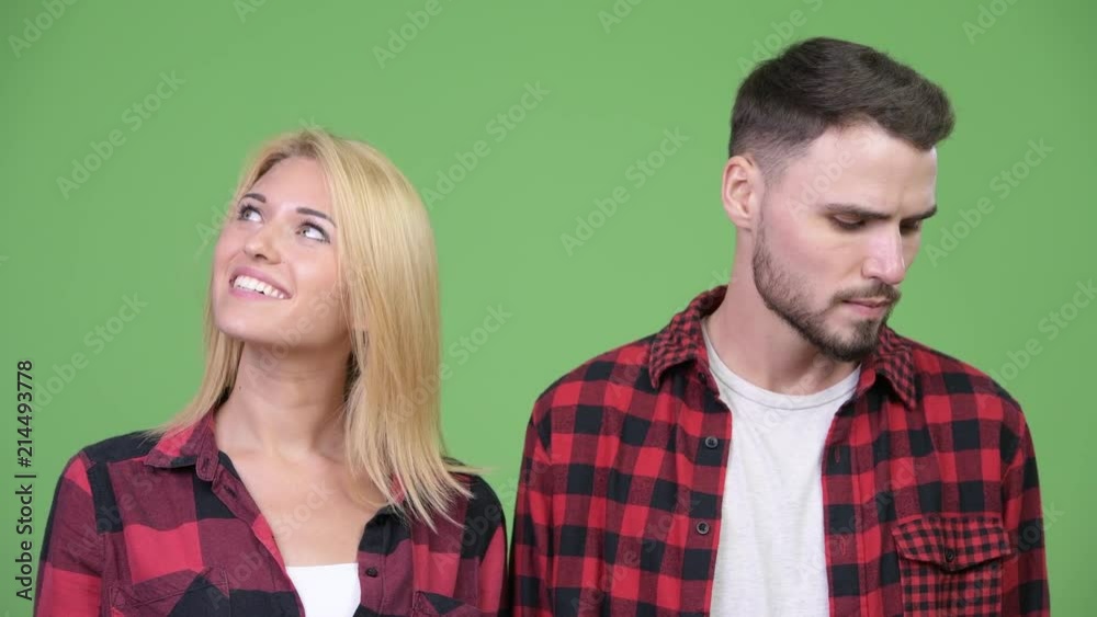 Young sad man thinking together with young happy woman Young sad man thinking together with young happy woman