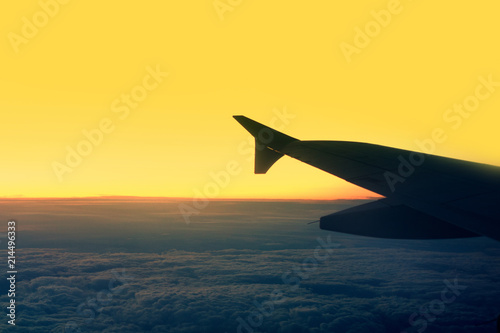 Passenger airplane.  View from airplane window on the wing during  sunset over the clouds. Business trip. Travel concept.