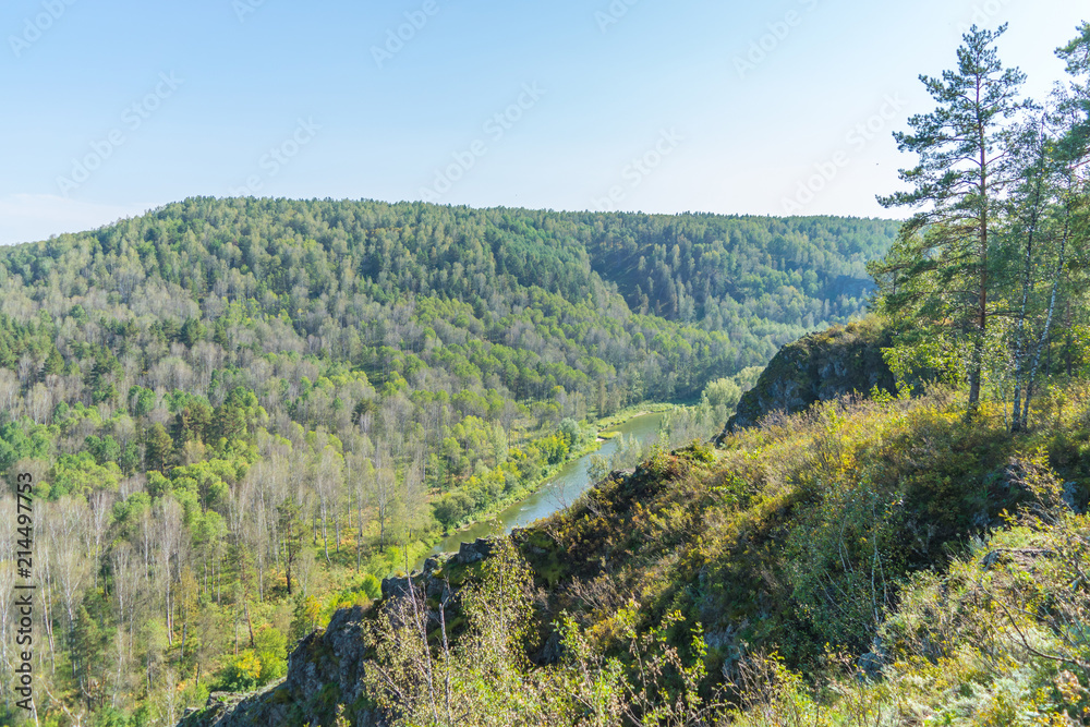 Mountain river in Siberia between the hills and mountains in the early autumn