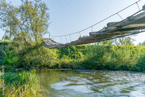 Suspended wooden pedestrian bridge across the river from below