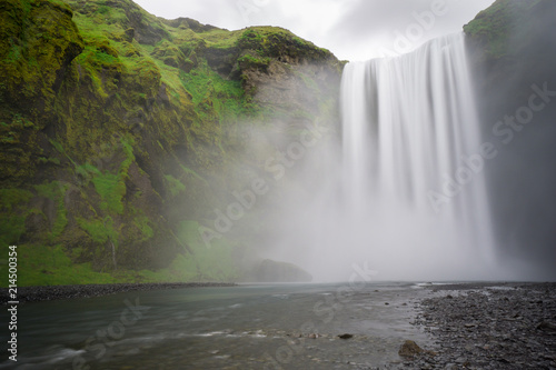 Iceland - Skogafoss waterfall and river with green steep face