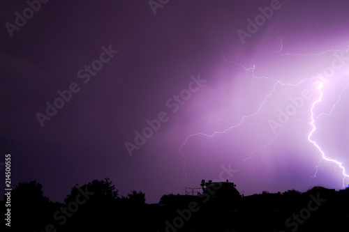 flash of lightning in the night sky color it in an incredibly beautiful violet color illuminating the trees