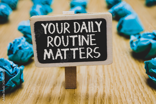 Handwriting text writing Your Daily Routine Matters.. Concept meaning Have good habits to live a healthy life Stand blackboard with white words behind blurry blue paper lobs woody floor. photo