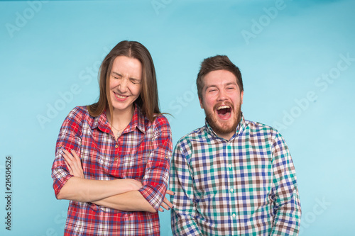 Funny young couple laughing and fooling around together on blue background. © satura_