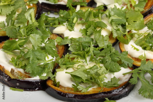 Sliced roasted eggplants with mayonnaise and cilantro in a porcelain plate
