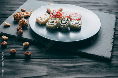 Traditional oriental sweets and nuts: hazelnuts, cashews on a dark wooden background. Turkish dessert is the Rakhat locus. View from above. Place under the text. photo