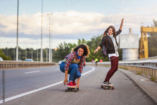 Skateboard girls riding long-boards down the road