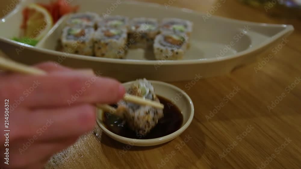Fresh delicious sushi on plate on table in restaurant. Woman eating healthy food. Fresh delicious sushi on plate on table in restaurant. Woman eating healthy food.