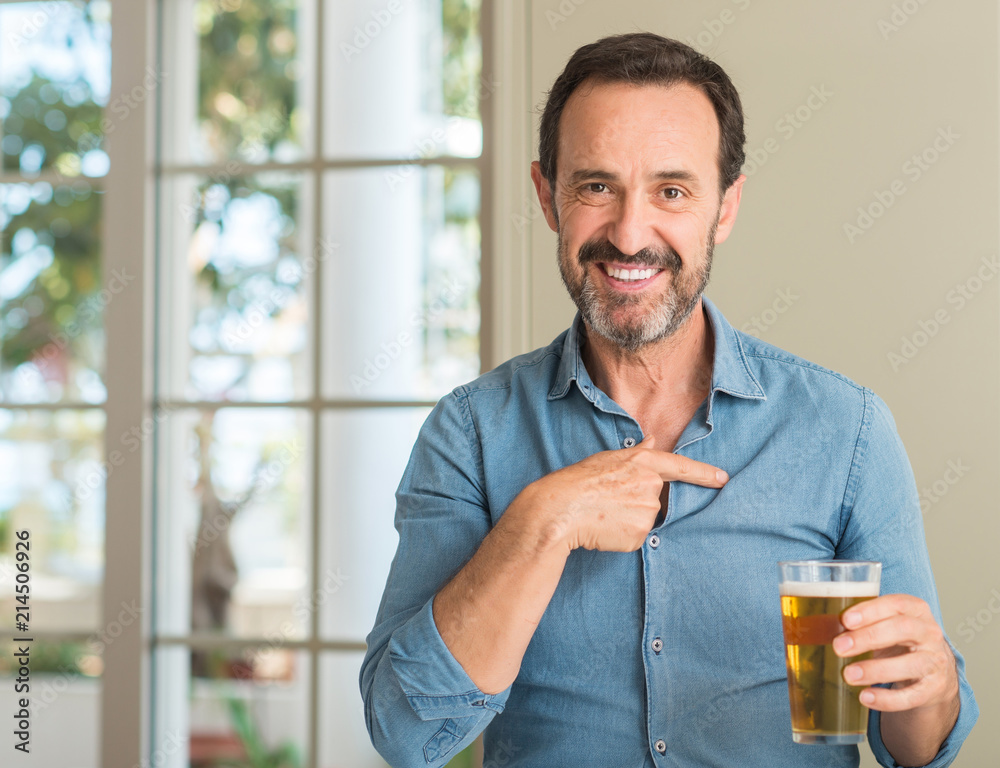 Middle age man drinking beer with surprise face pointing finger to himself Middle age man drinking beer with surprise face pointing finger to himself