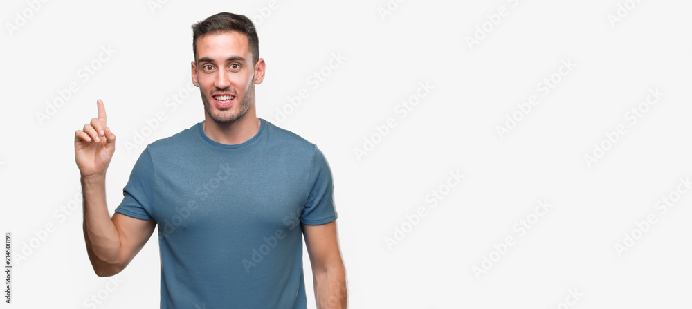Handsome young casual man showing and pointing up with finger number one while smiling confident and happy. Handsome young casual man showing and pointing up with finger number one while smiling confident and happy.