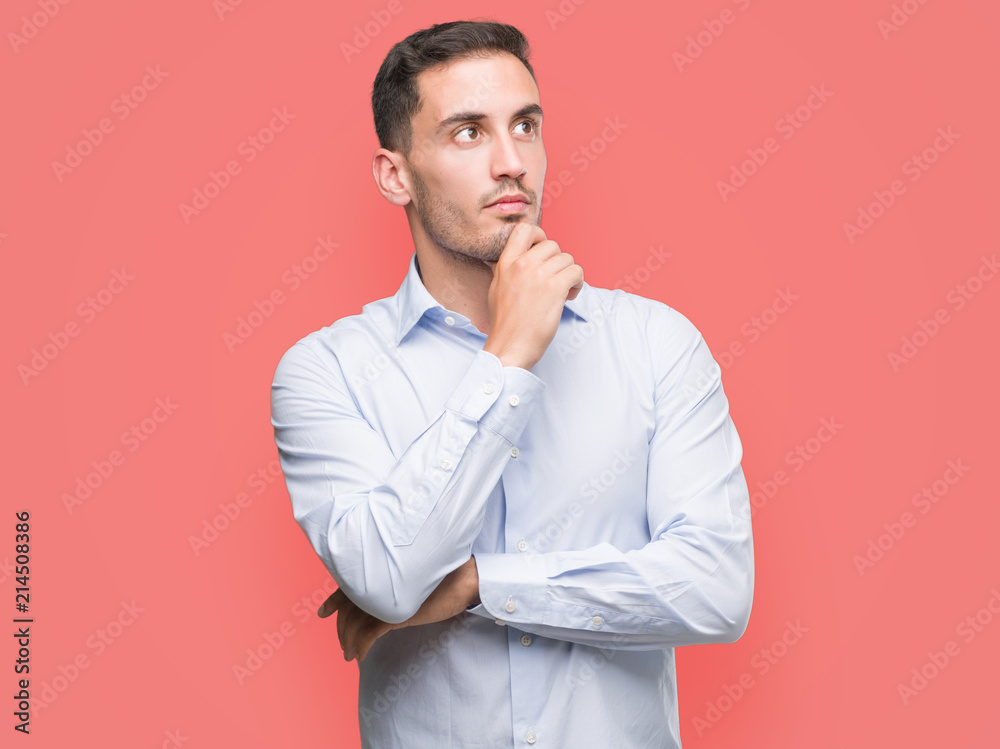 Handsome young businessman looking confident at the camera with smile with crossed arms and hand raised on chin. Thinking positive. Handsome young businessman looking confident at the camera with smile with crossed arms and hand raised on chin. Thinking positive.