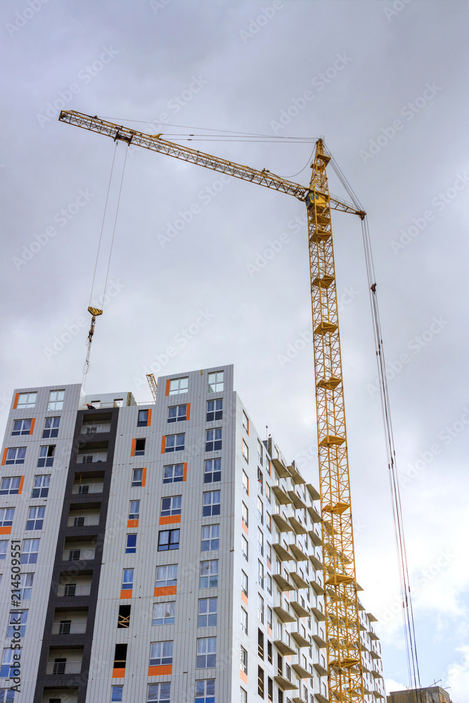 Construction crane and house under construction. Vertical composition Construction crane and house under construction. Vertical composition
