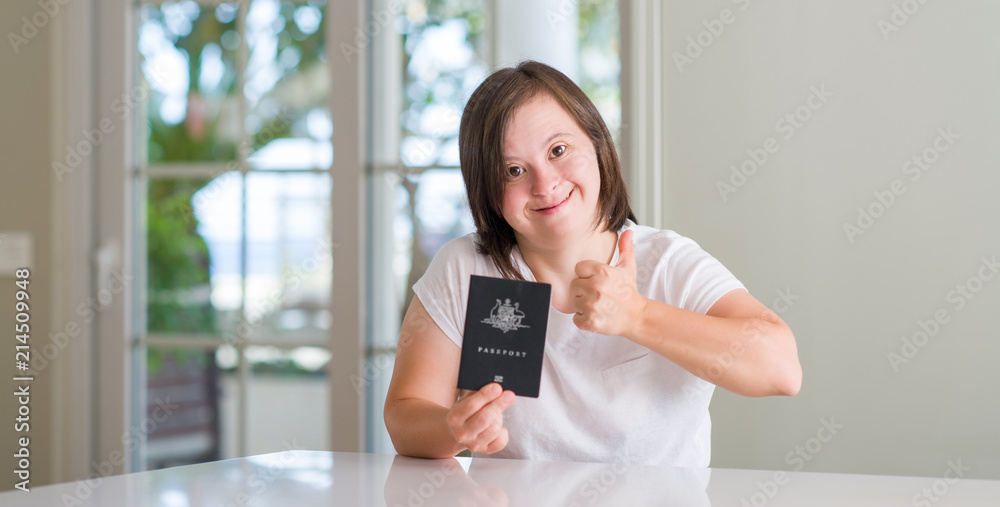 Down syndrome woman at home holding australian passport happy with big smile doing ok sign, thumb up with fingers, excellent sign