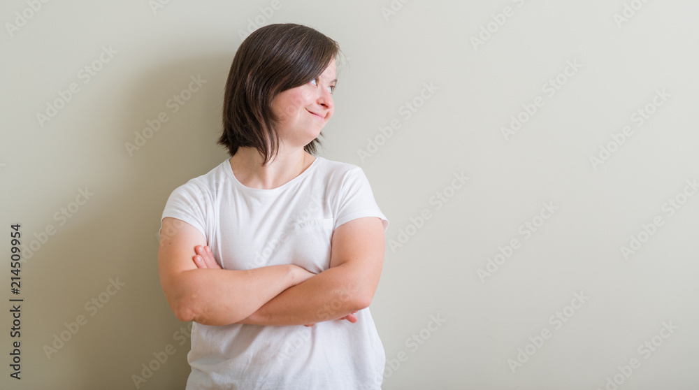Down syndrome woman standing over wall smiling looking side and staring away thinking. Down syndrome woman standing over wall smiling looking side and staring away thinking.