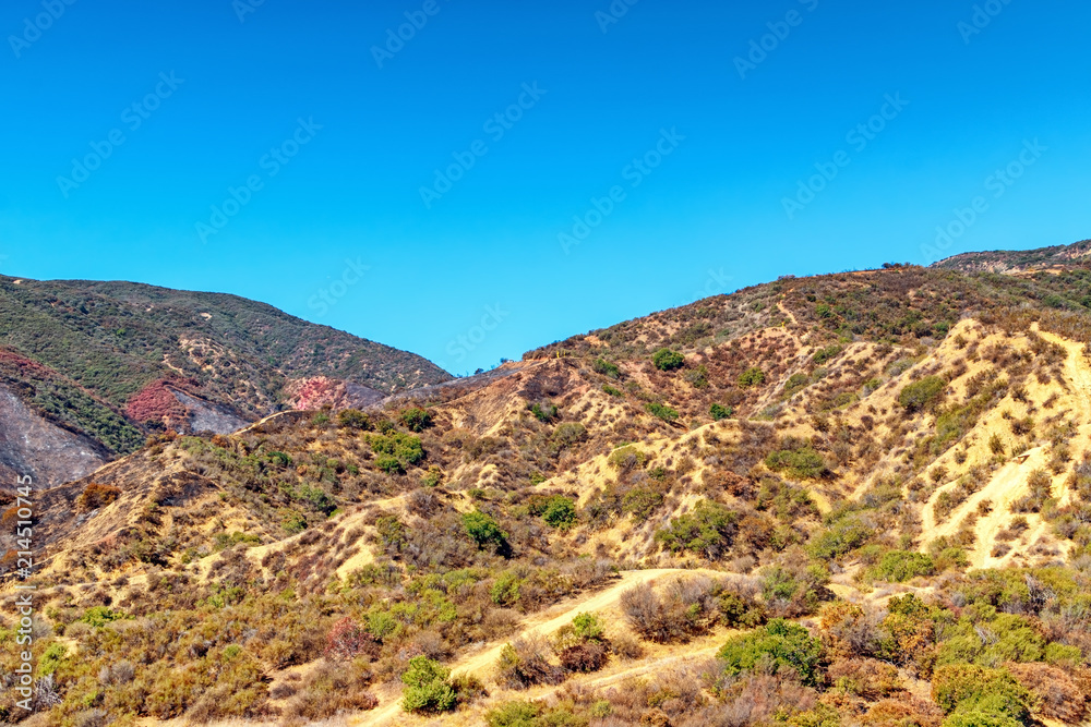 Bright summer morning in Southern California mountains with fire damage and fire retardant covering hills