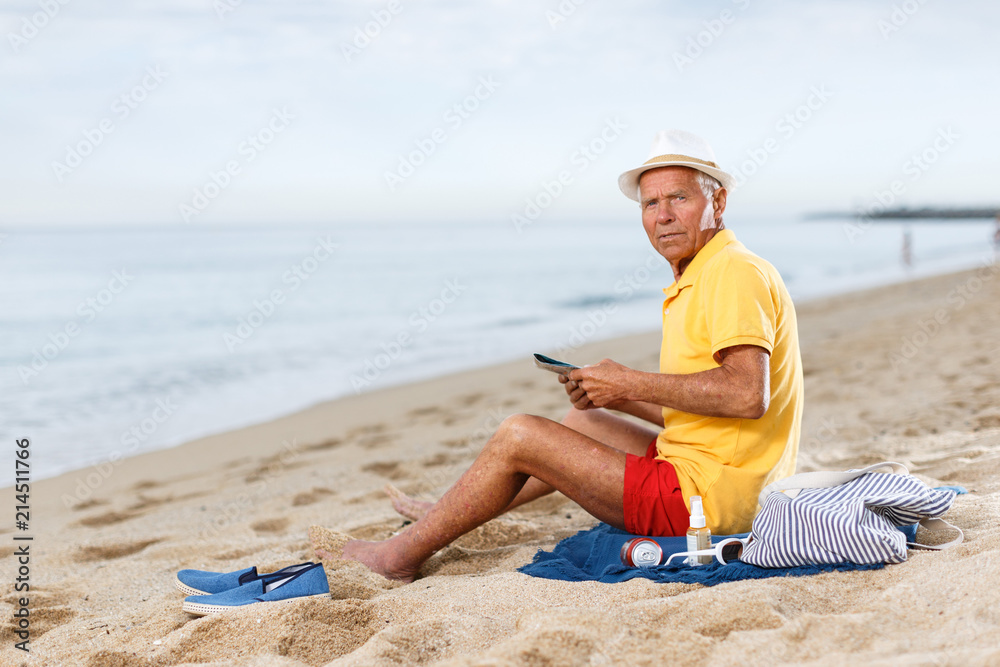 Fine mature man  sitting and looking at booklet
