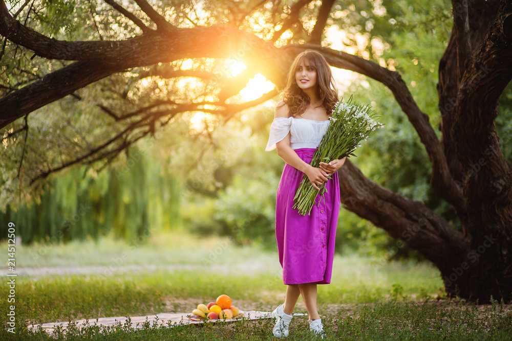 Young woman with bouquet of wildflowers in hands against a background of sunset. Young woman with bouquet of wildflowers in hands against a background of sunset.