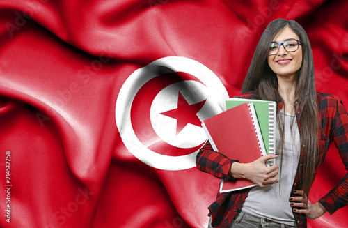 Happy female student holdimg books against national flag of Tunisia photo