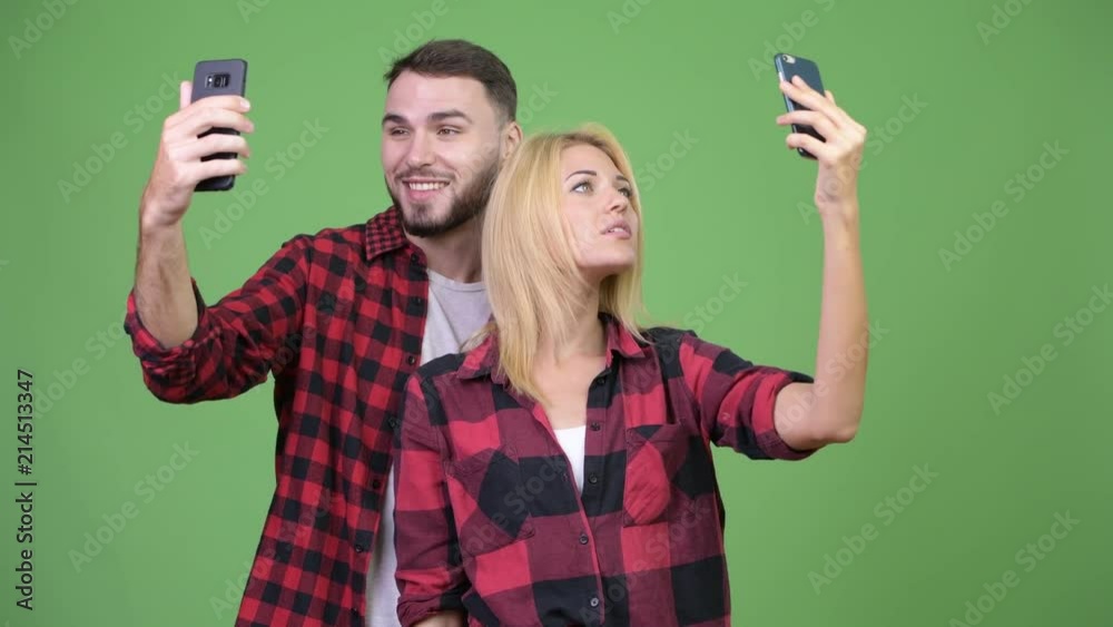 Young couple using phone and taking selfies together Young couple using phone and taking selfies together