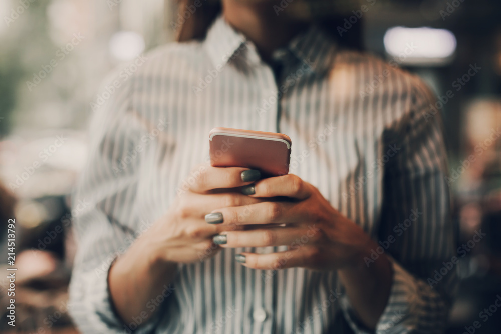 A pictute of girl in blouse standing and holding phone in hands. She is typing. Cut view A pictute of girl in blouse standing and holding phone in hands. She is typing. Cut view
