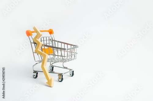 A supermarket cart and a wooden arrow down on a white background. The concept of the fall of prasada and the deterioration of consumer sentiment. Decline in purchasing power.