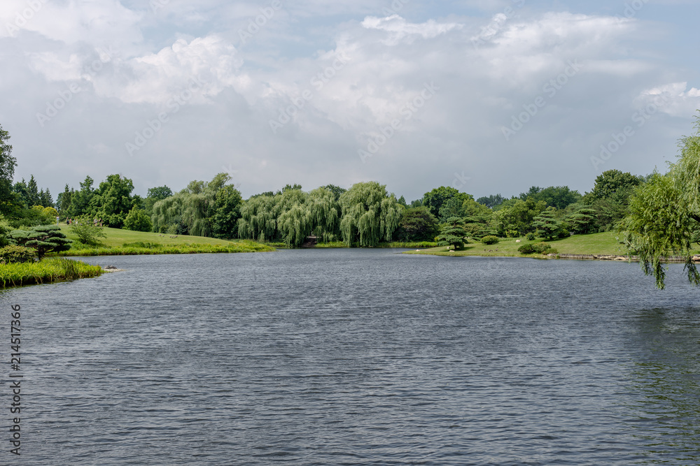 Big clouds overlooking green trees and smooth water Big clouds overlooking green trees and smooth water