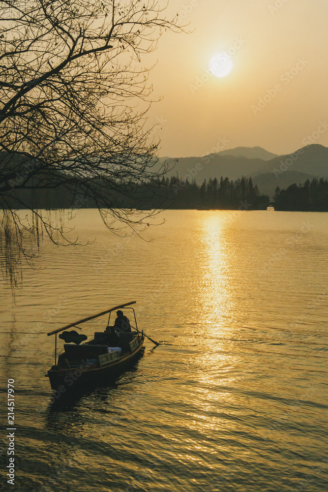 A boat traveling on the water of West Lake in Hangzhou, China at sunset
