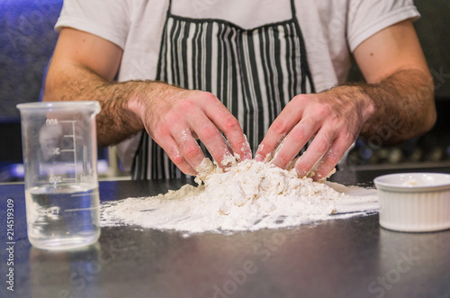 Man preparing pizza dough on black granite table
