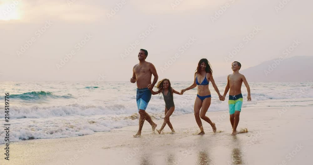 Happy young family walking on the beach at sunset Happy young family walking on the beach at sunset